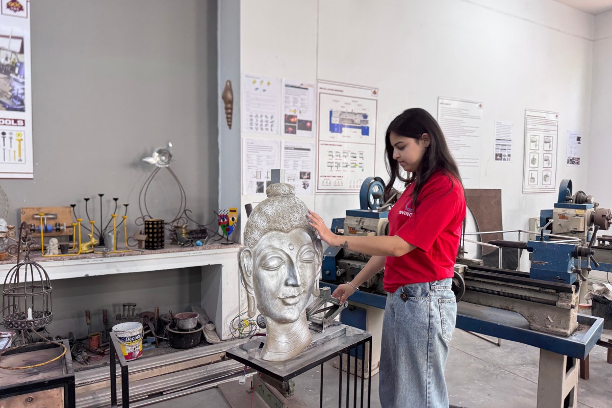 Student sculpting metal Buddha in workshop at CODE